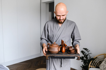 Wall Mural - a man holds a tray with a set for a Chinese tea ceremony