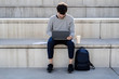 © Giorgio Fochesato/Westend61 - Man sitting on outdoor stairs using laptop