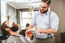 Barber Spraying Aftershave On Beard Of A Customer