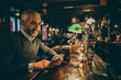 © Martin Benik/Westend61 - Man sitting at counter of a pub using smartphone