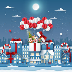 Origami Paper art of cute Christmas character on balloon in town with snowing, Merry Christmas and Happy New Year