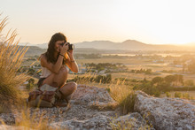 Young Woman Taking A Picture With Her Camera On Top Of A Mountain
