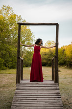 Young Woman In A Red Dress On A Wooden Platform