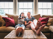 © Cavan Images - Two teenage girls sitting on a couch with their feet up watching tv