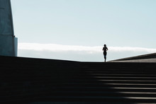 Silhouette Of Woman Running On Stairs With Blue Sky In Background