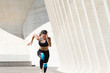 © Cavan Images - Upper body of female athlete in sportswear running fast on concrete