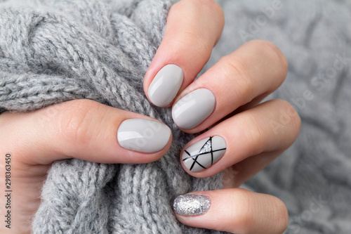 Fotomural Females hand with modern manicure holds gray knitted sweater close up