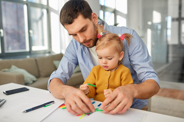 Wall Mural - multi-tasking, freelance and fatherhood concept - working father with baby daughter at home office