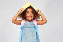 Childhood, School And Education Concept - Happy Little African American Girl With Book And Backpack Over Grey Background