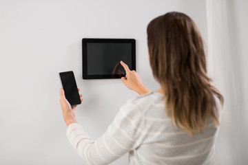 Poster - automation, internet of things and technology concept - woman using tablet pc computer and smartphone at smart home