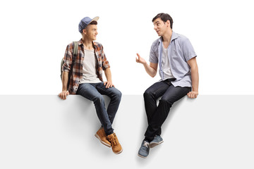 Wall Mural - Two young men sitting on a panel and talking