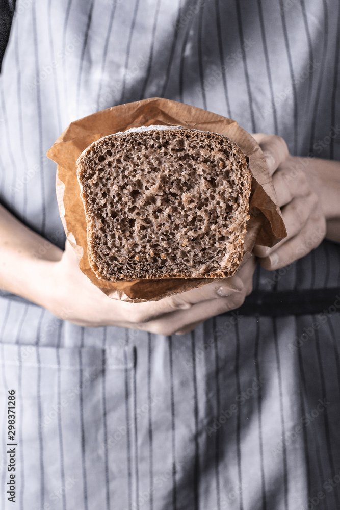 Obraz na płótnie Trzymanie bochenka chleba w dłoniach na szarym tle w stylu rustykalnym w salonie