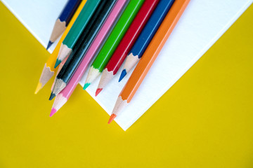 Colorful drawing pencils on yellow background