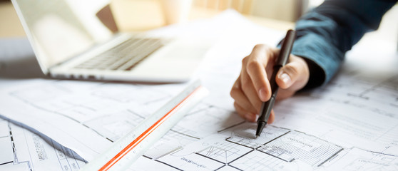 Close up woman hand working of Architect sketching project on blueprint at site construction work. Concept of architect, engineer in the office desk construction project banner