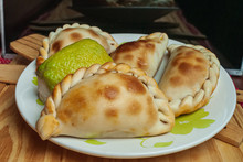 Homemade Empanadas (detailed Close-up Shot; Selective Focus) Typical Of The Argentine Countryside Gastronomy, On White Plate On Rustic Wooden Table.