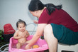 © AlivePhoto - Asian woman washing her daughter in bathtub, Happy adorable baby girl taking a bath in pink tub