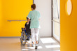 Soignante accompagne une personne âgée en fauteuil roulant dans un établissement de soins