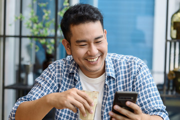 Smart Asian man using smartphone in cafe and drinking coffee, lifestyle concept.