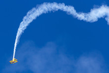 Vintage Biplane Does Stunt With Smoke Trails In The Blue Sky.