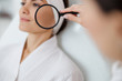 © Yakobchuk Olena - Beautician examining lady skin with magnifying glass