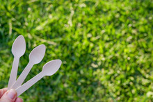Hands Holding Disposable Wooden Teaspoon On Green Grass Background. Reduce Reuse Recycle. Say No To Plastic Cutlery
