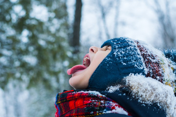 Wall Mural -  boy stuck out his tongue and catches snowflakes