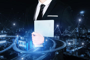 business man in modern black suit holding mobile smart tablet with effect network link connection and graph chart of stock market graphic diagram, digital technology, internet communication concept