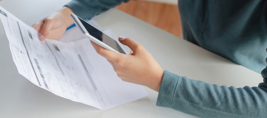 panoramic banner. hand of young woman using calculator for calculating family budget cost bills on desk in home office, plan money cost saving, investment, business finance, expenses, income concept