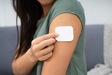 woman applying patch on her arm