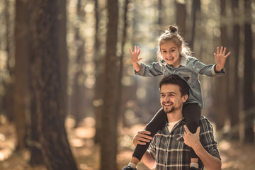 Dad and daughter walking in the autumn forest.