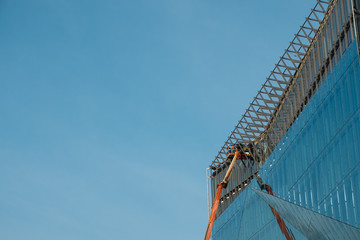 Canvas Print - cranes on glass facade office building under construction -