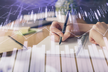 Financial forex graph drawn over hands taking notes background. Concept of research. Multi exposure