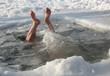 man dives into a lake in winter in ice water