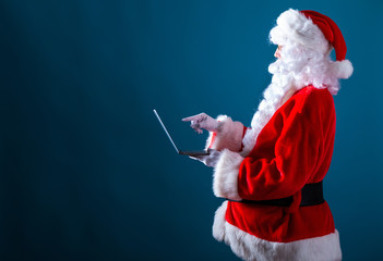 Santa using a laptop on a dark blue background