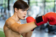 © Kawee - Caucasian handsome man wearing boxing gloves punching ahead with one fist in gym or fitness club. The bear chested nice body boxing male looking forward with serious face. Fitness for health concept.