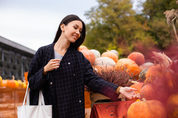 Young attractive casual woman at farm shop happily looking for pumpkin for Halloween day