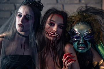 Three women in a carnival costumes of a vampire bride, bloody mutant and witch.