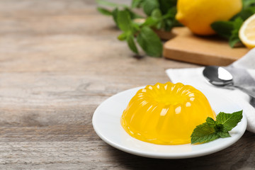 Delicious fresh yellow jelly with mint on wooden table. Space for text