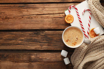 Flat lay composition with cup of coffee and sweets on wooden table, space for text. Cozy winter