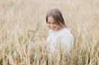 © Svyatoslav Balan - Beautiful young girl in a white sweater sits in a wheat field and smiles cheerfully.