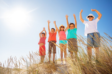 Canvas Print - Many kids on the sand beach happy lift hands up