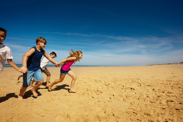 Wall Mural - Boys and girls run on the sand sea beach