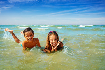 Wall Mural - Boy and girl play in ocean waves on beach vacation