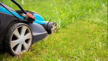 Electric Lawn Mower Machine In Garden On Grass. Garden And Lawn Care Theme. Banner Format With Copy Space