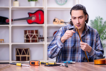 Young handsome repairman repairing violin