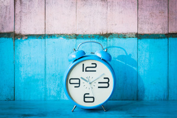 Blue vintage alarm clocks on blue wooden table and light blue and pink background wall