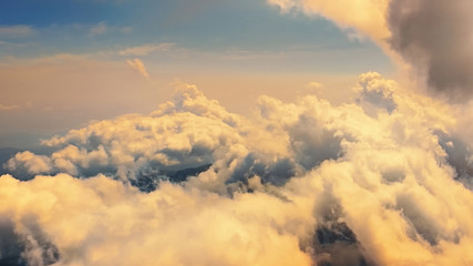 Wall Mural - Flying through heavenly beautiful cloudscape. Picturesque of warm tone fluffy clouds moving softly on the pale blue sky in the evening sunshine. Direct view from the cockpit.