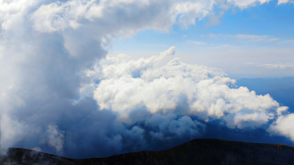 Wall Mural - Flying through heavenly beautiful cloudscape. of warm tone fluffy clouds moving softly on the pale blue sky in the evening sunshine. View from the cockpit.