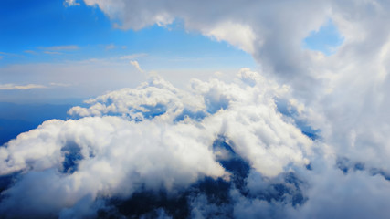Wall Mural - Flying through heavenly beautiful cloudscape. of warm tone fluffy clouds moving softly on the pale blue sky in the evening sunshine. View from the cockpit.