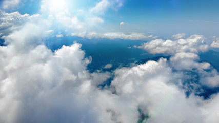 Wall Mural - Flying through heavenly beautiful sunny cloudscape. Picturesque of white fluffy clouds moving softly on the clear blue sky in pure sunshine. Direct view from the cockpit.